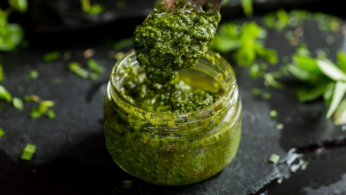 Ein Glas mit Thai-Basilikum-Pesto vor einem dunklen Hintergrund