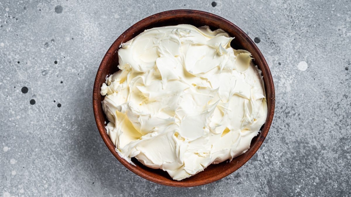 Eine holzfarbene Schüssel mit Mascarpone drinnen oder einer Mascarpone-Alternative.