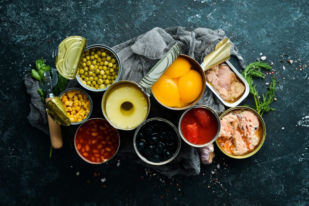 Viele geöffnete Konservendose mit Obst, Gemüse und Fleisch in der Draufsicht.