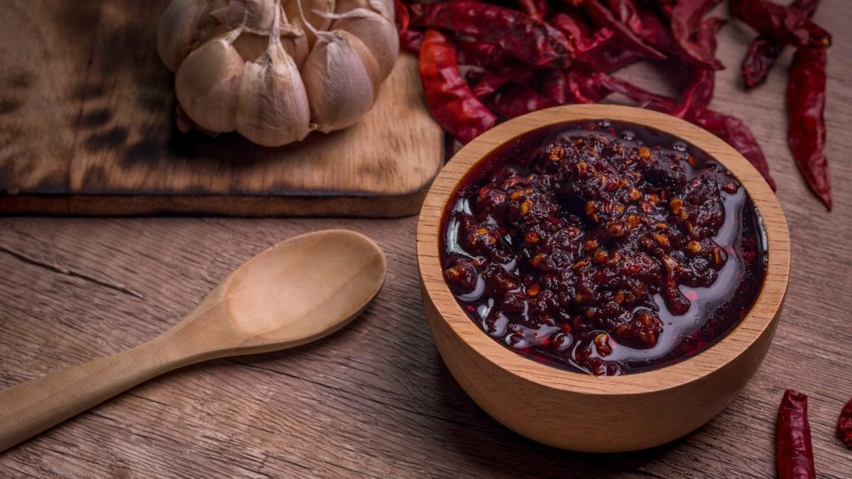 Eine Holzdose mit Nam Prik Pao, einer thailändischen Chilipaste und frischem Knoblauch sowie Chili