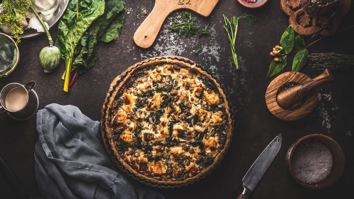 eine vegane Mangold-Quiche in der Draufsicht, drumherum viele verschiedene Zutaten.
