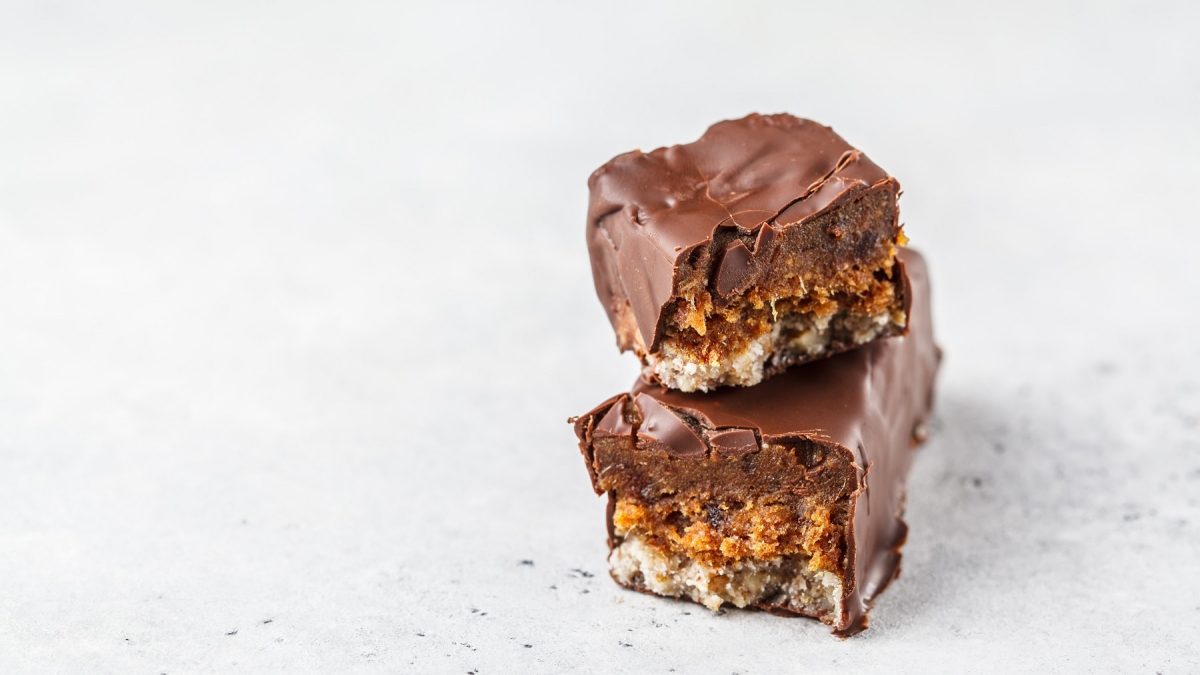 ein durchgebrochener selbst gemachter veganer Snickers übereinander gestapelt.