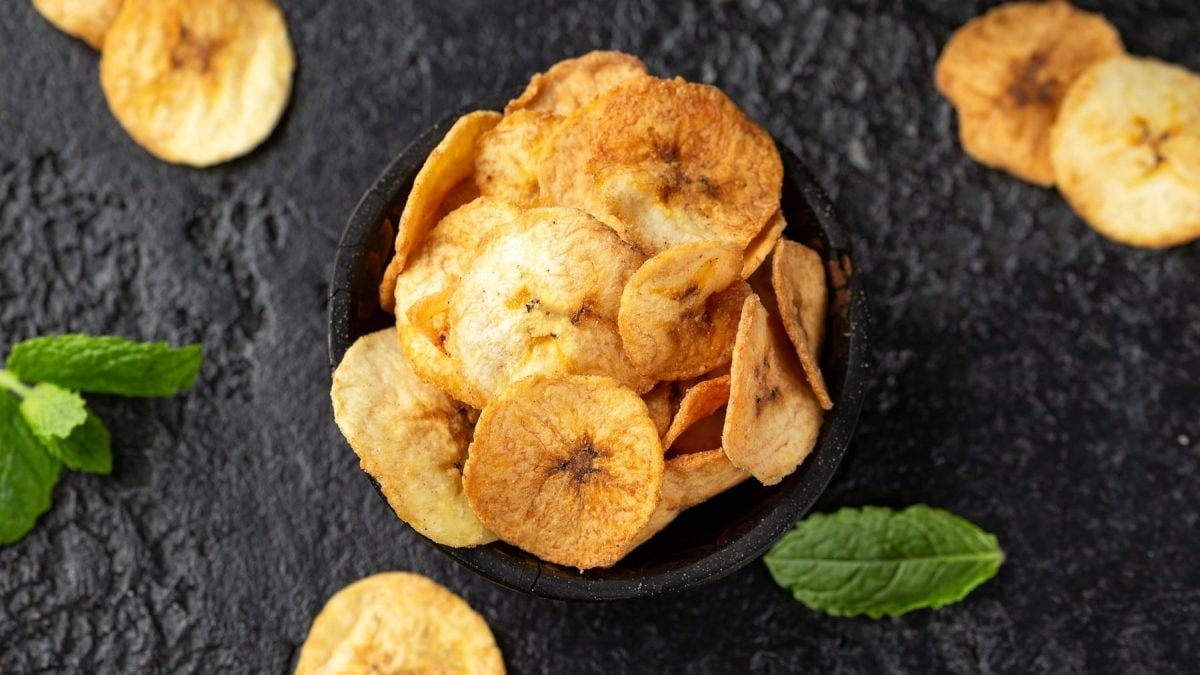 Kleine Schale voller Chicharritas garniert mit Minzblättern vor schwarzem Hintergrund.