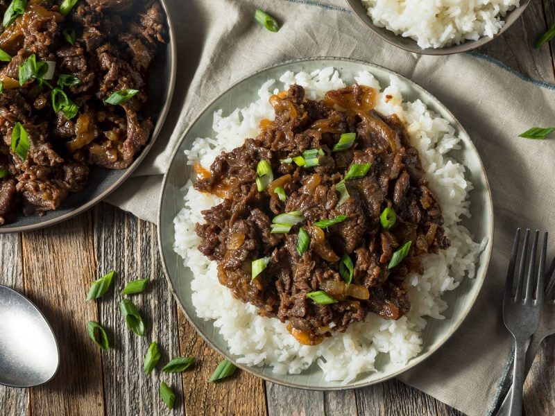 Ein Teller mit Reis und Bulgogi auf einem grauen Tuch.