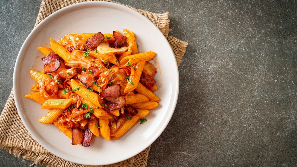 Ein weißer Teller mit Kimchi Pasta mit Bacon gefüllt.