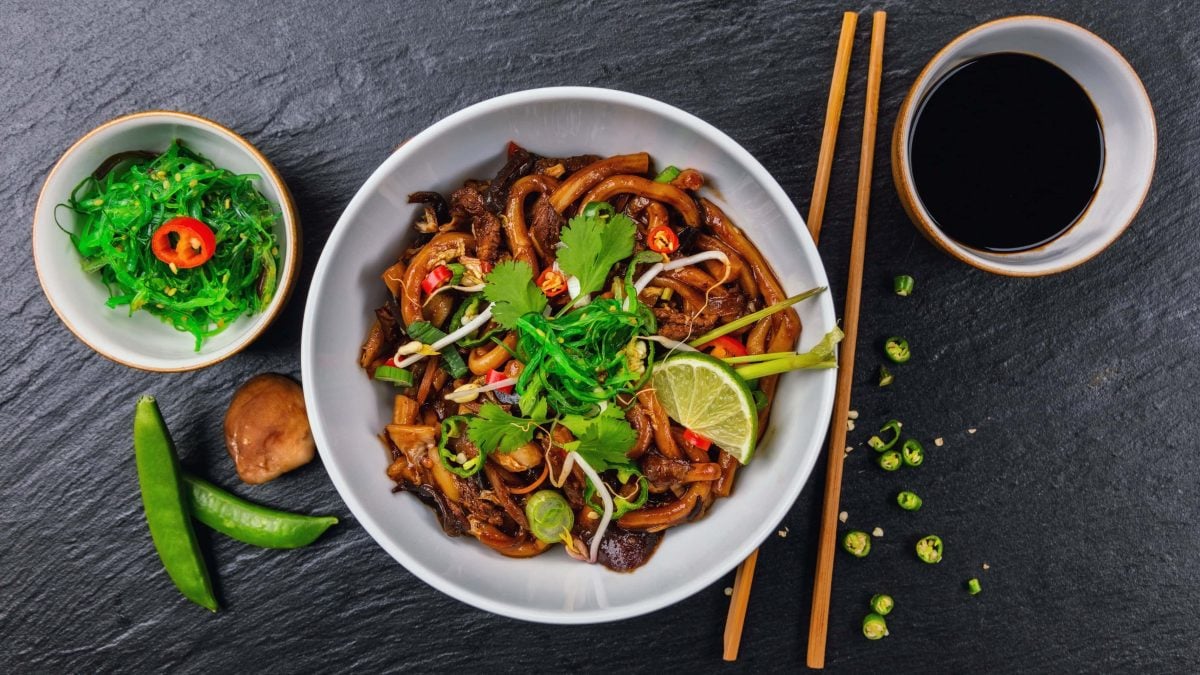 Eine weiße Schüssel mit Udon-Nudeln in Limetten-Sojasauce.