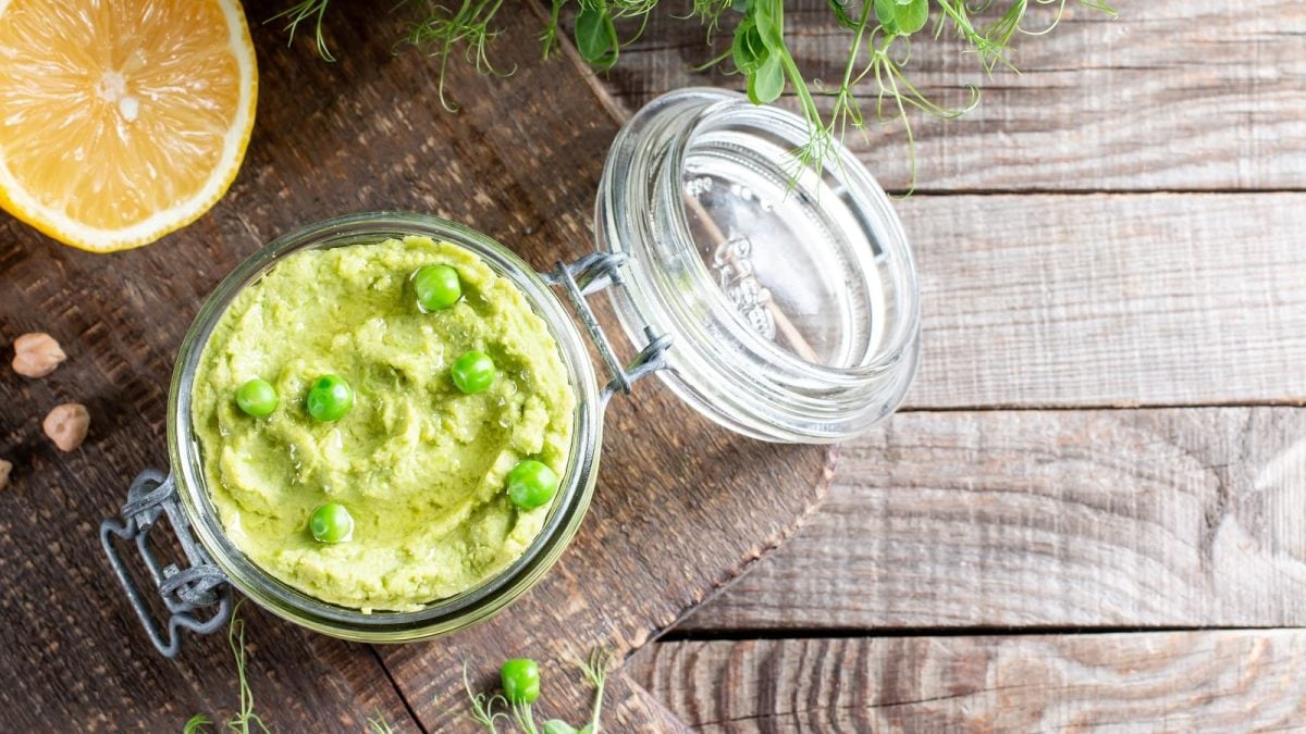 Ein Glas mit Erbsen-Guacamole auf Holzhintergrund