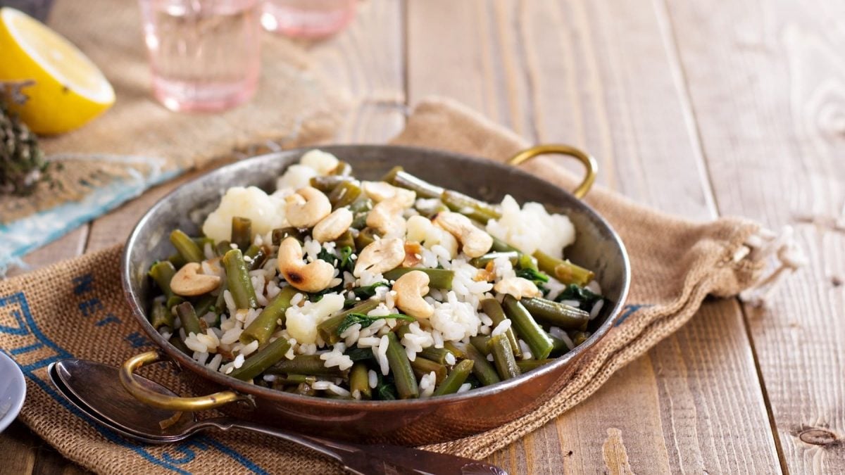 Eine kleine Pfanne grüne Bohnen mit Reis und Cashews.