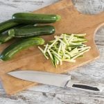 Julienne schneiden von Zucchini auf einem Holzbrett.