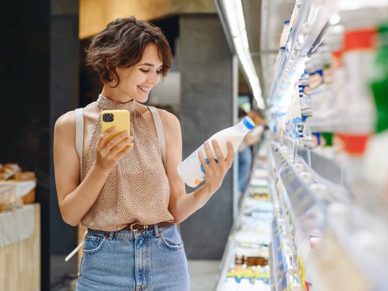 Eine Frau prüft im Supermarkt das Mindesthaltbarkeitsdatum eines Produktes.