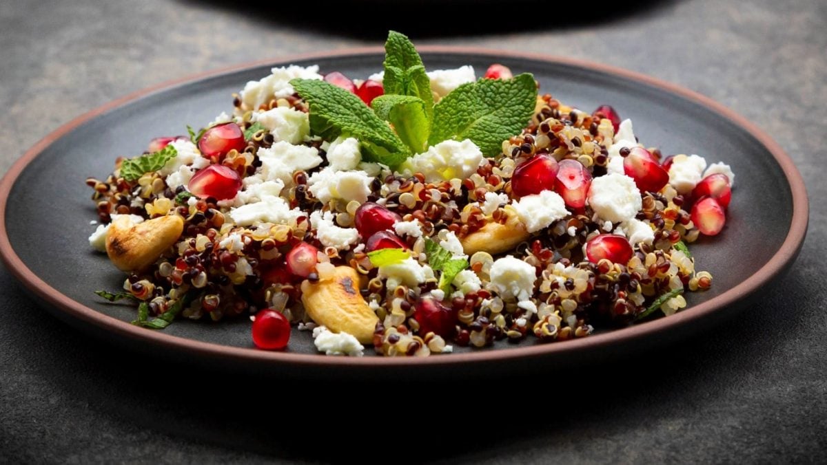 Ein schwarzer Teller mit dem Quinoa auf einem dunkelgrauen Untergrund.