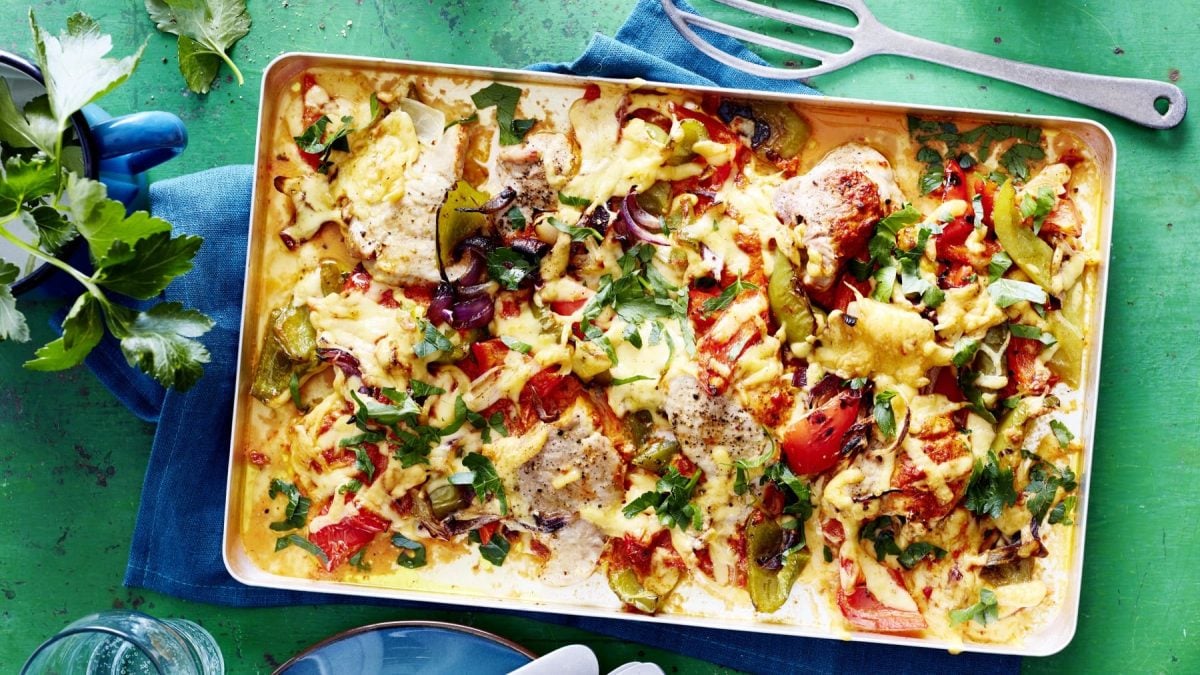 In einer Ofenform sind Paprika-Schnitzelchen aus dem Ofen vor grünem Hintergrund.