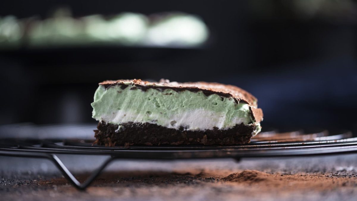 Ein Stück Schokoladen-Minzcreme-Kuchen auf einem Gitter vor dunklem Hintergrund.