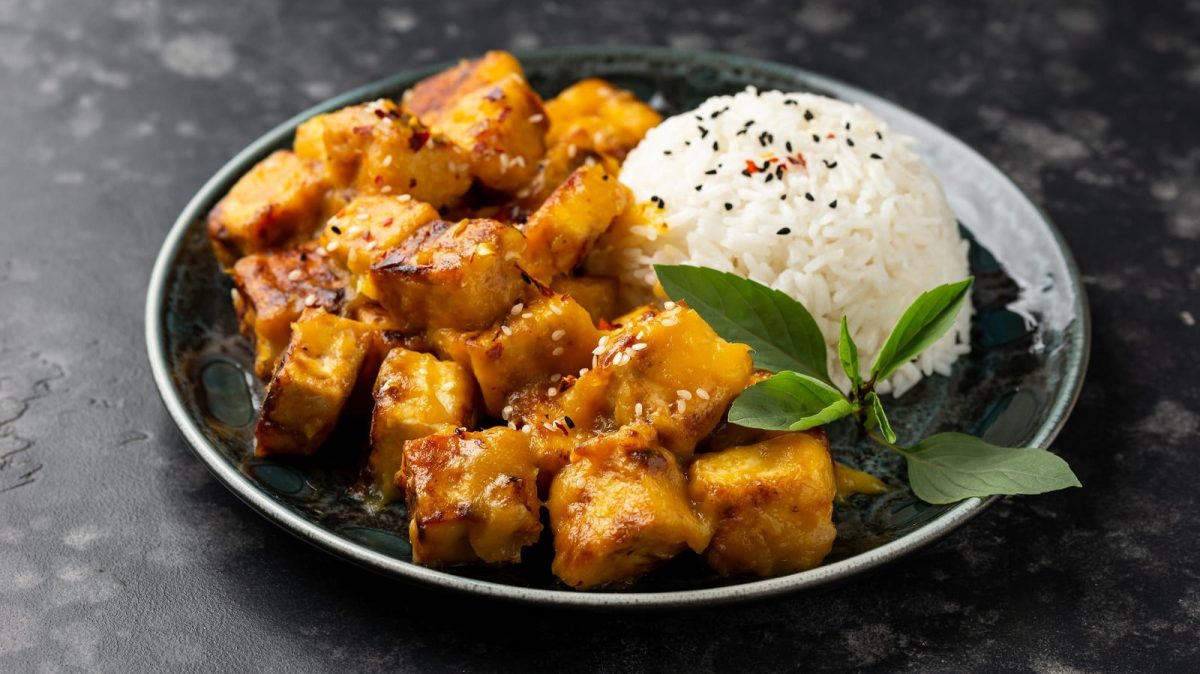Ein dunkler Teller mit Reis und Sticky Mango Tofu