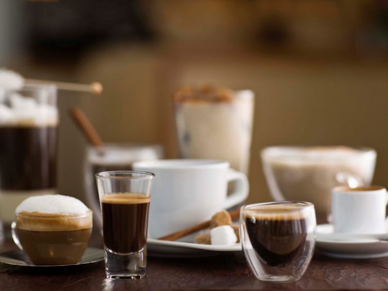 Zum Tag des Kaffees diverse Kaffeespezialitäten auf einem Tisch. Frontalansicht.
