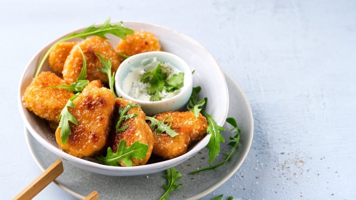 Eine Schale panierte Tempeh Nuggets mit einem Dip in der Mitte.