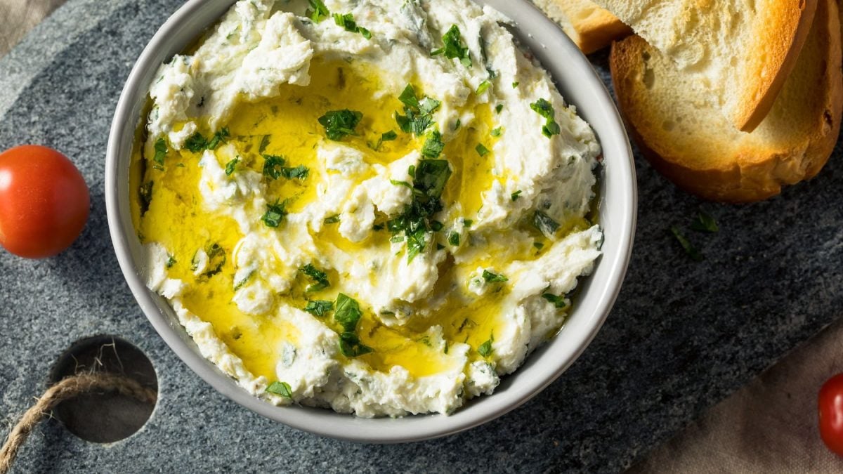 Eine Schale Whipped Feta mit Öl und frischen Kräutern.