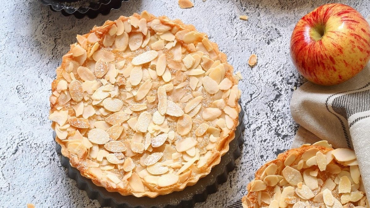 Apfel-Schüttelkuchen mit Mandeln auf grauer Oberfläche.