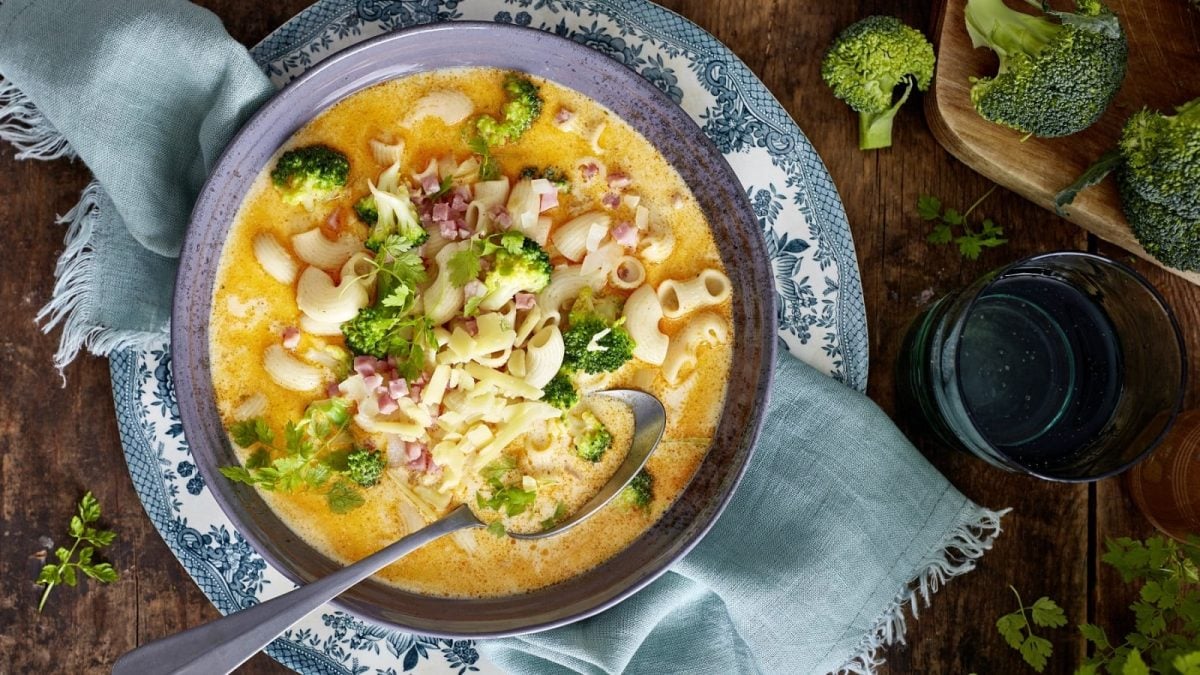 In einer Schüssel ist eine Mac-and-Cheese-Suppe angerichtet. Sie ist mit Kerbel garniert.