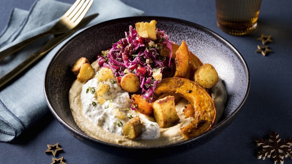 Mezze mit gebackenem Kürbis, Fetacreme, Hummus, Rotkohlsalat und knusprigem Brezelcrunch, serviert in einer dunklen Keramikschale.