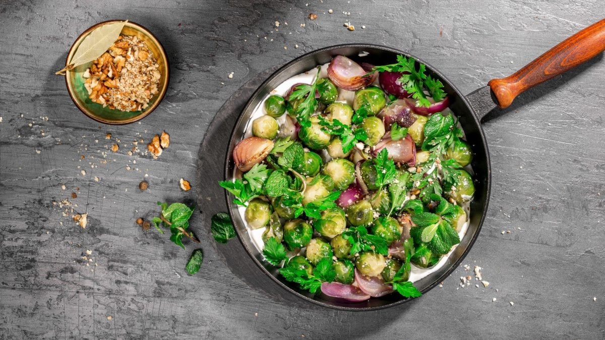 Rosenkohlpfanne mit frischer Joghurt-Limetten-Sauce auf grauem Untergrund.