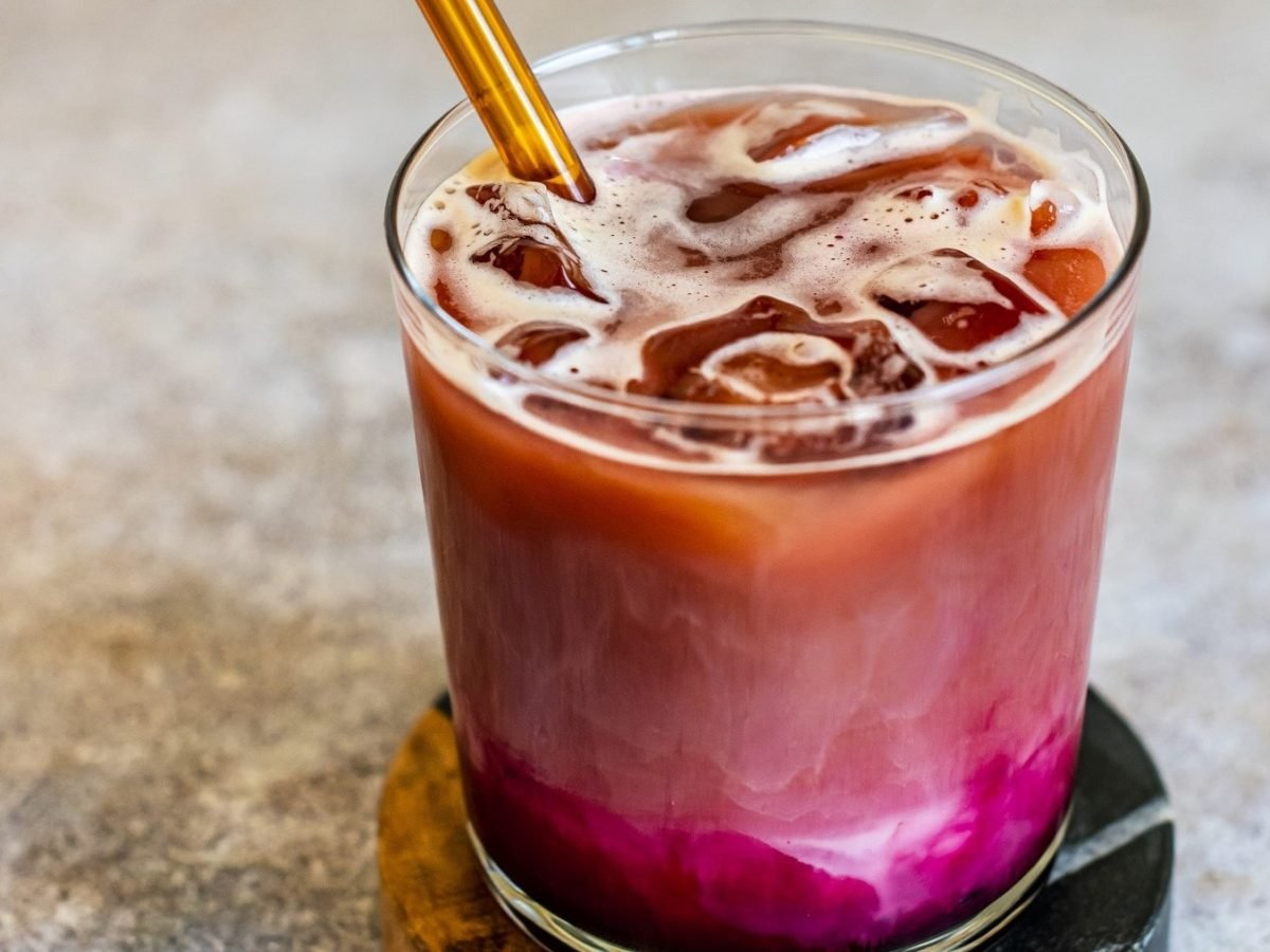 Rote-Bete-Latte mit Eiswürfeln in einem Drink-Glas auf Marmortisch.