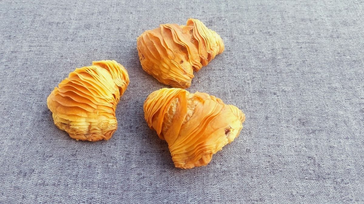 Drei Sfogliatelle auf einem grauen Untergrund.