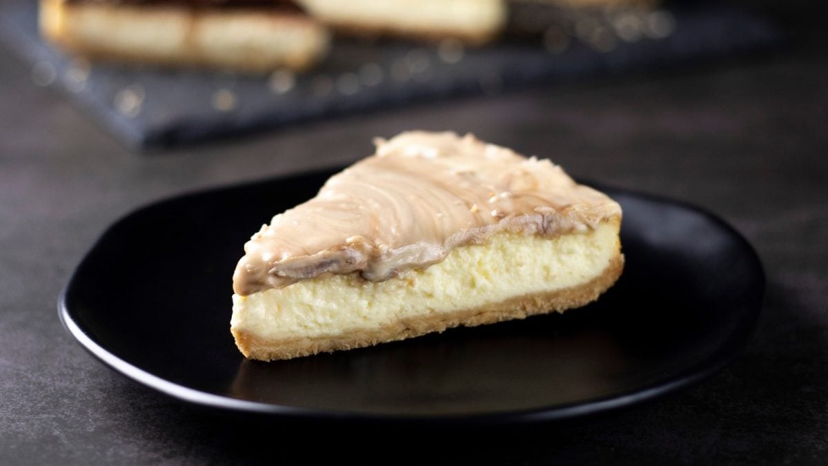 Ein schwarzer Teller mit einem Stück White Chocolate Cheesecake