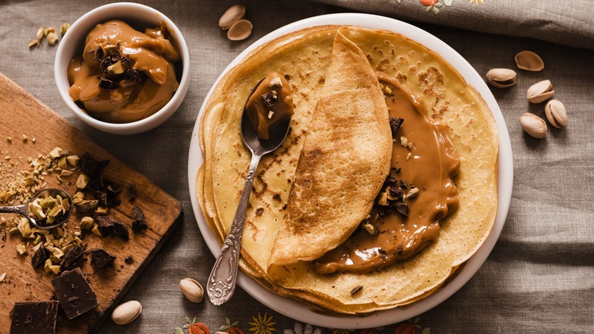Eierkuchen mit selbstgemachtem Dulce de Leche auf einem Teller, garniert mit Schokolade und Nüssen.