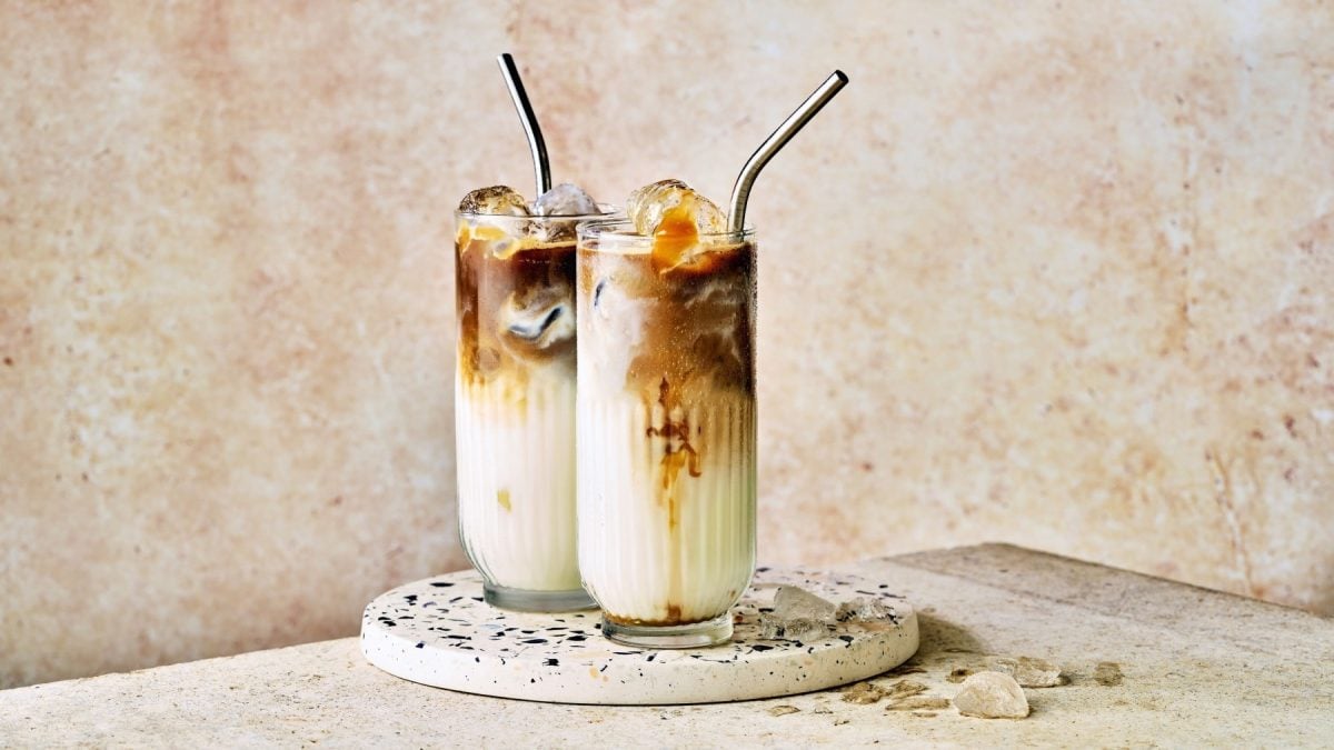 Zwei Gläser mit Eis-Karamell-Macchiato auf einer Keramikplatte.