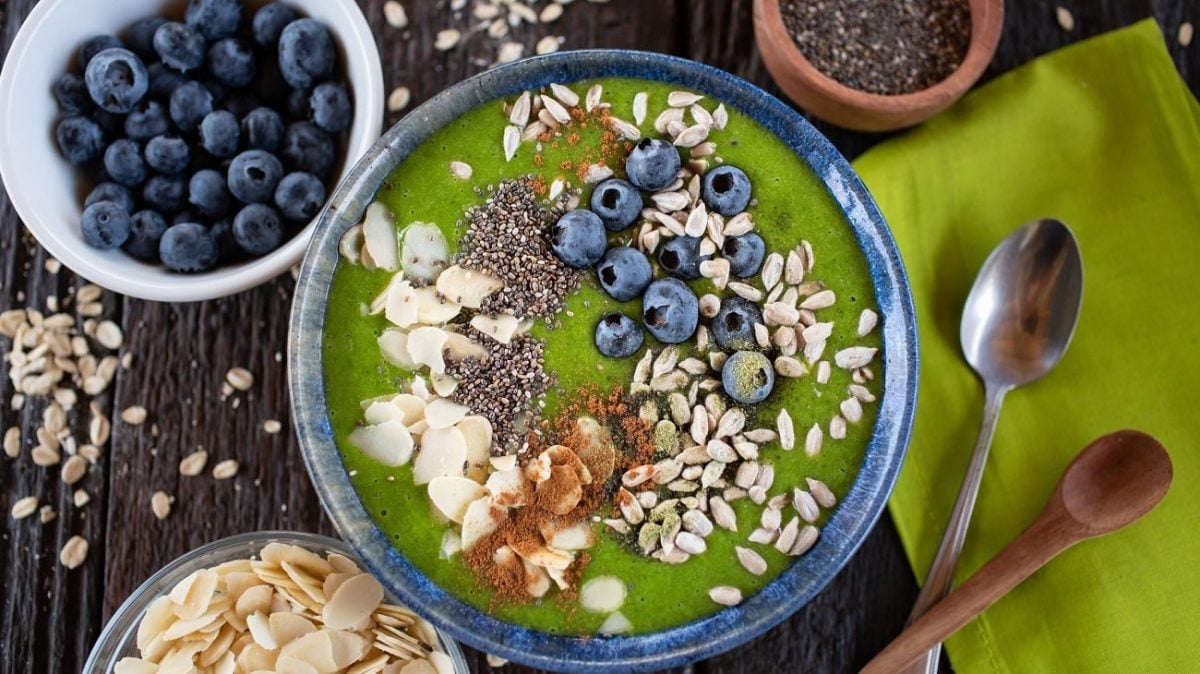 Draufsicht: Eine Schüssel mit einer Flüssigkeit und Blaubeeren, mandeln und Sonnenblumenkernen.