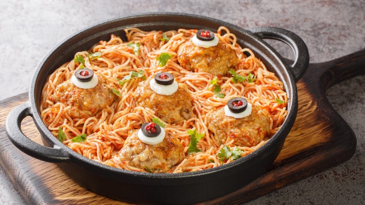 Eine gusseiserne Pfanne mit der Pasta auf einem Holztisch.