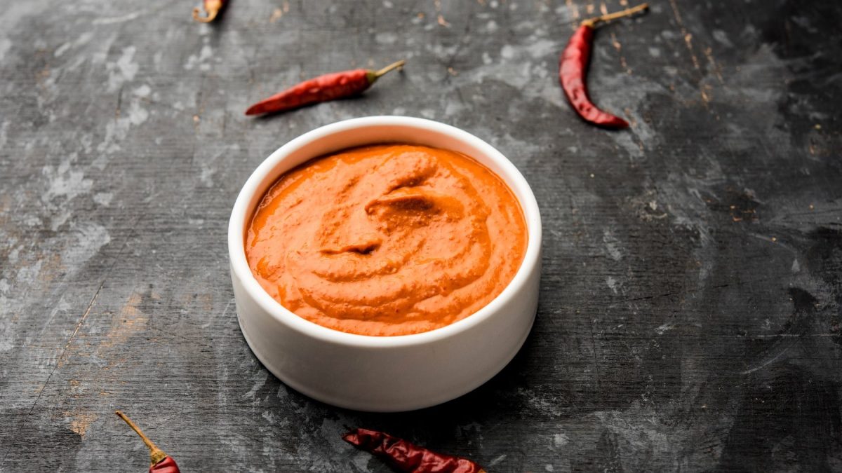 Eine kleine weiße Schale mit der Piri Piri Sauce auf dunkelgrauem Untergrund..