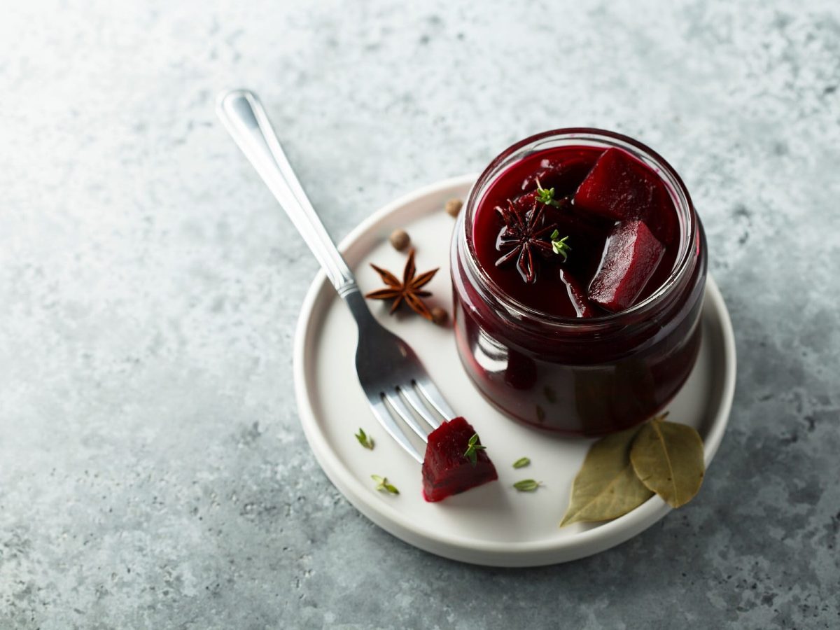 Rote Bete haltbar gemacht im Glas auf einem Teller, eine Gabel mit einem Stück Bete daneben.