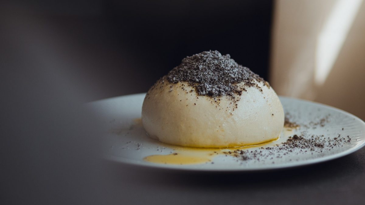 Ein veganer Germknödel mit Mohn und zerlassener Margarine auf einem Teller.
