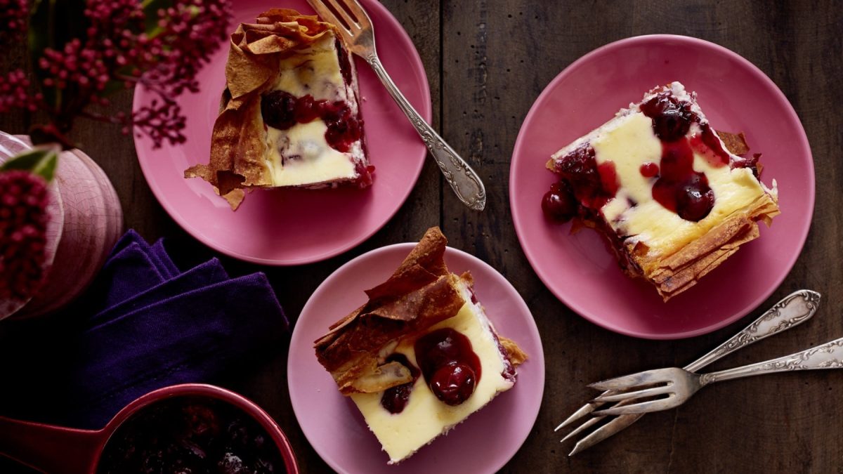 Auf einem Tisch stehen mehrere Teller mit Gewürz-Kirsch-Käsekuchen. Sie sind cremig und saftig.