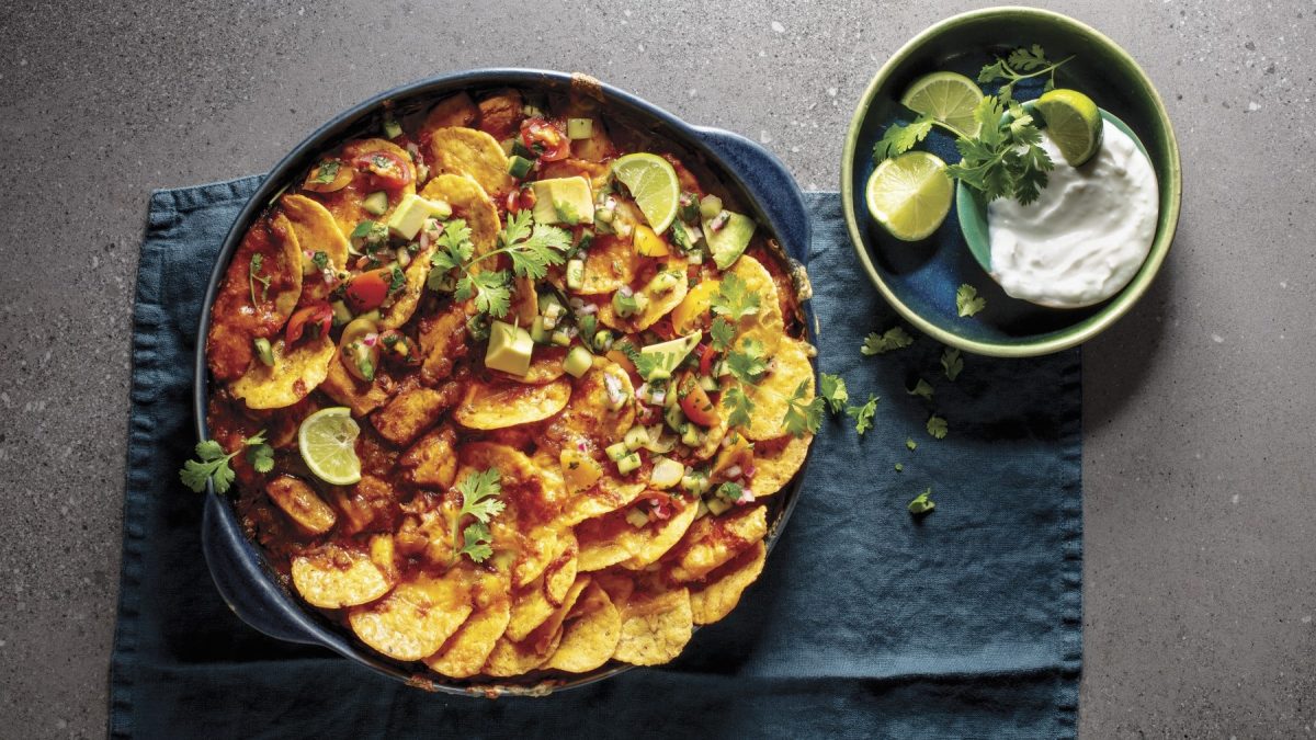 Hühnchen-Nachos mit Kokos-Dip, frischem Koriander und Limette, serviert auf einem blauen Küchentuch.
