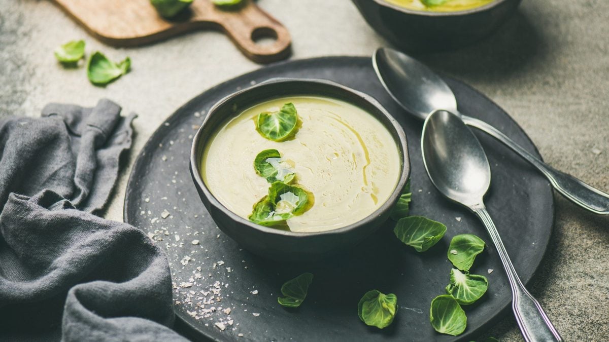 Rosenkohlsuppe in schwarzer Schüssel auf schwarzem Teller.