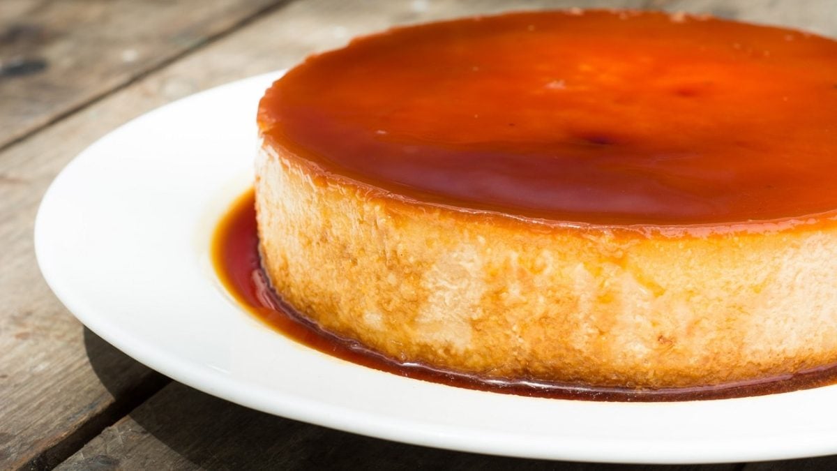 Frontalansicht: Eine flacher runder kuchen der am rand hell und oben dunkler steht auf einem weißen Teller. Der Kuchen wird nur zur zum Teil abgebildet.