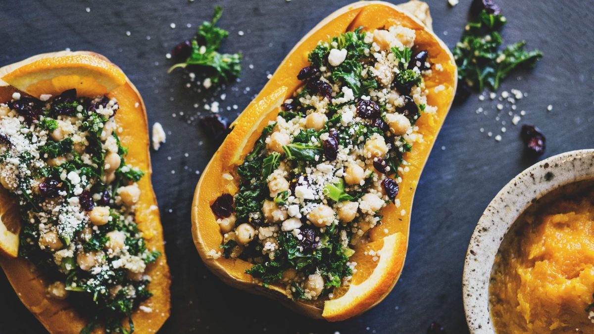 Gefüllter Butternut mit Grünkohl, Quinoa und Cranberrys auf einer dunklen Schieferplatte.