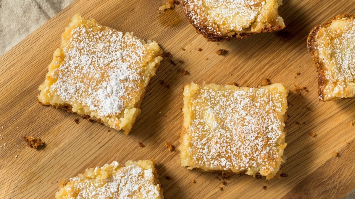 Ein Holzbrett mit mehreren Stücken Gooey Butter Cake darauf.