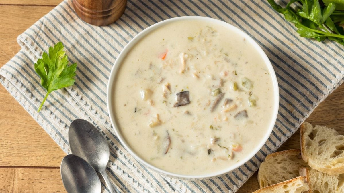Eine runde Schüssel mit Hähnchen-Reis-Cremesuppe auf einem Geschirrtuch.