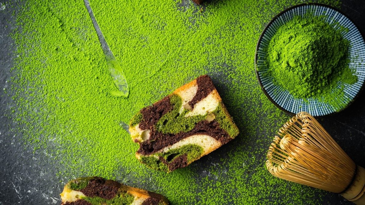 Ein Stück mit Matcha-Marmorkuchen neben Matchapulver.