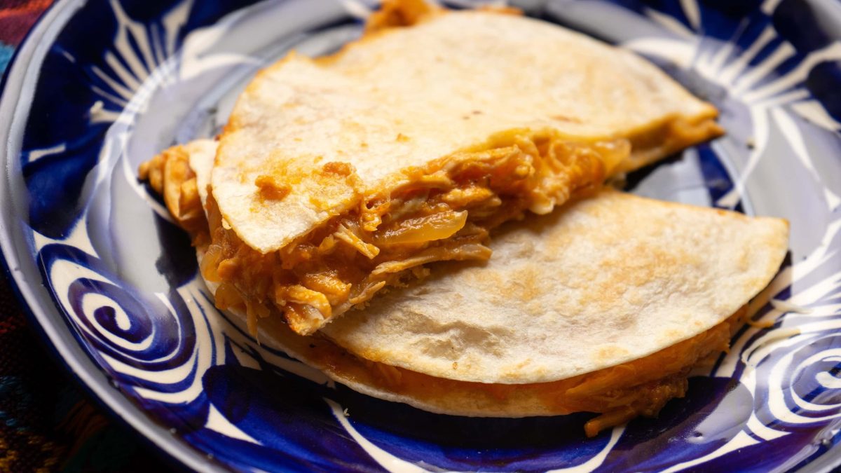 Quesadilla Tinga de Pollo auf blau-weißem Teller angerichtet. Draufsicht.