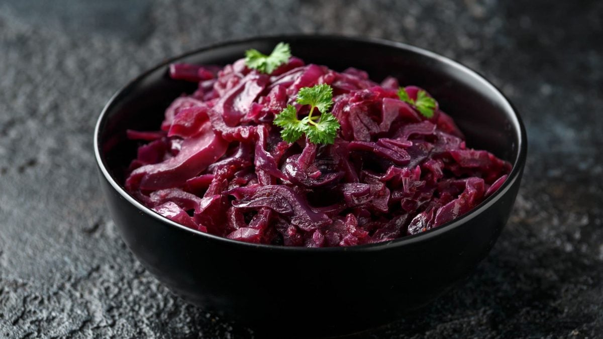 Eine schwarze Schüssel mit Rotkohl auf einem Schieferuntergrund.