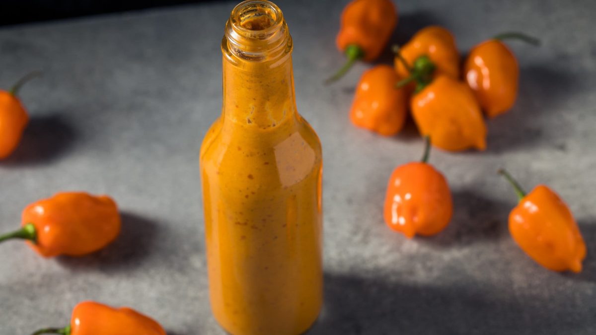 Salsa Habanero mit Cashewmus in Glasflasche. Im Bild gelbe Habaneros. Frontalansicht.
