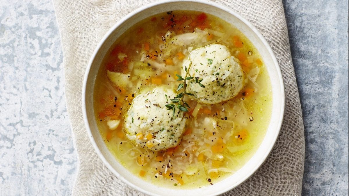 Draufsicht: eine weiße Schüssel mit einer klaren Suppe in der zwei Knödel sind.