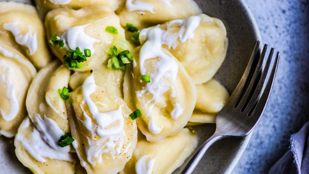 Maultaschen mit Schmandsauce auf grauem Teller.