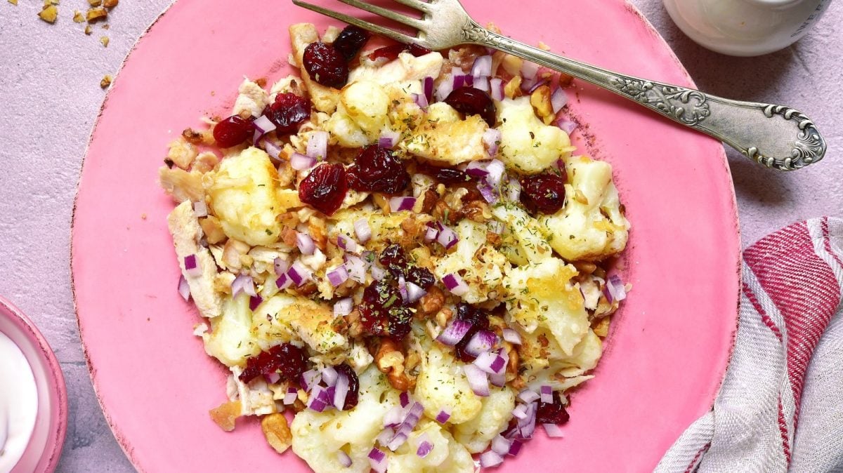 Ein rosa Teller mit Blumenkohl-Salat mit Cranberries.