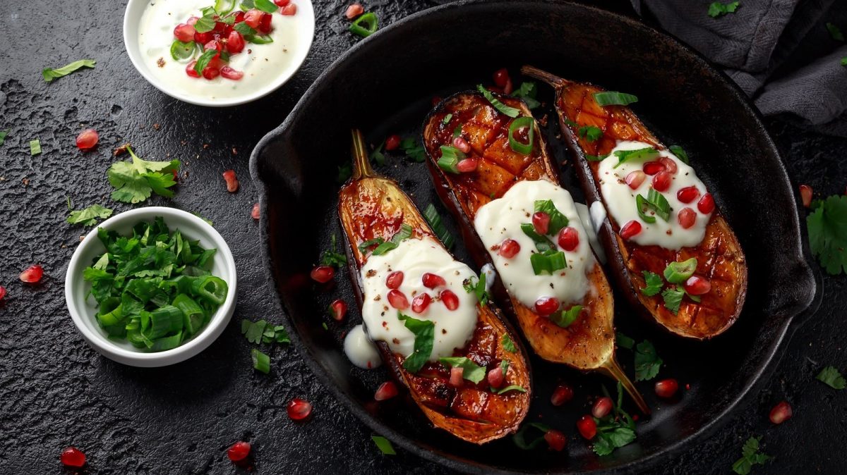 Eine schwarze Pfanne mit gegrillter Aubergine mit Joghurtsauce